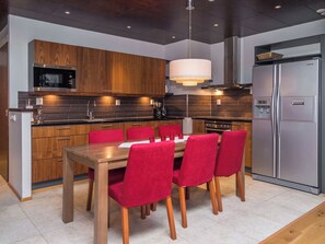 A modern kitchen with wooden cabinets, a stainless steel refrigerator, and a dining area with a wooden table and red chairs. - Tahko spa suites orange a 9 by Interhome (Nilsiä)