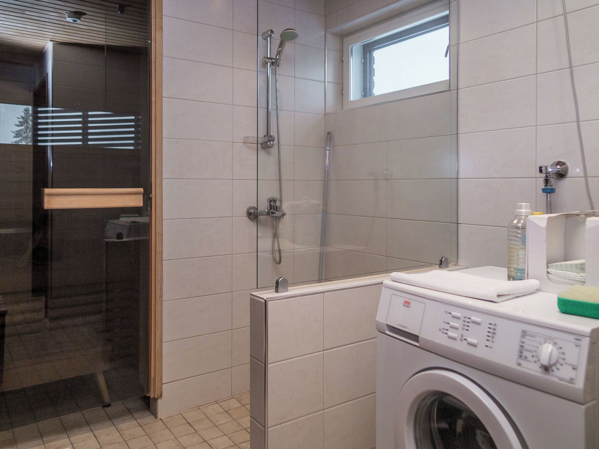 Une salle de bain avec une douche à parois de verre, un lave-linge et une fenêtre.