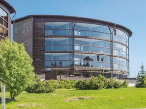 A modern building with a curved facade, large glass windows, and a wooden exterior.