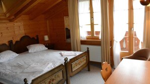 Una habitación de cabaña de madera con una cama, una mesa y un ventanal con cortinas.