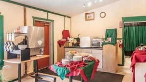 A kitchen with a coffee machine, microwave, and a table set with plates and food. - Ashland Valley Inn (Ashland)