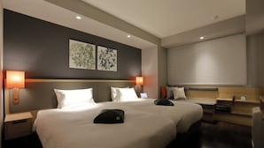 A hotel room with two beds, a bedside table with a lamp, a small desk with a chair, and a wall-mounted clock. - Hotel Forza Osaka Kitahama (Osaka)