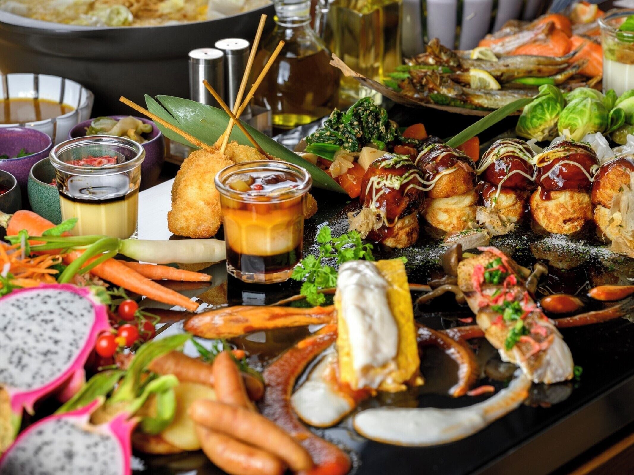 A variety of seafood dishes, including shrimp, crab, and other seafood, served on a black platter with dipping sauces and garnishes.