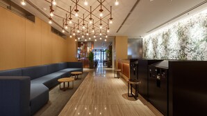 A modern lobby with a blue sofa, wooden flooring, and a bar area with a marble wall. - Hotel Forza Osaka Kitahama (Osaka)
