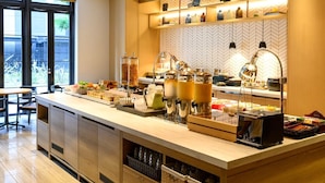A modern breakfast bar with a variety of food items and beverages, a coffee machine, and a view of the outdoors through large windows. - Hotel Forza Osaka Kitahama (Osaka)