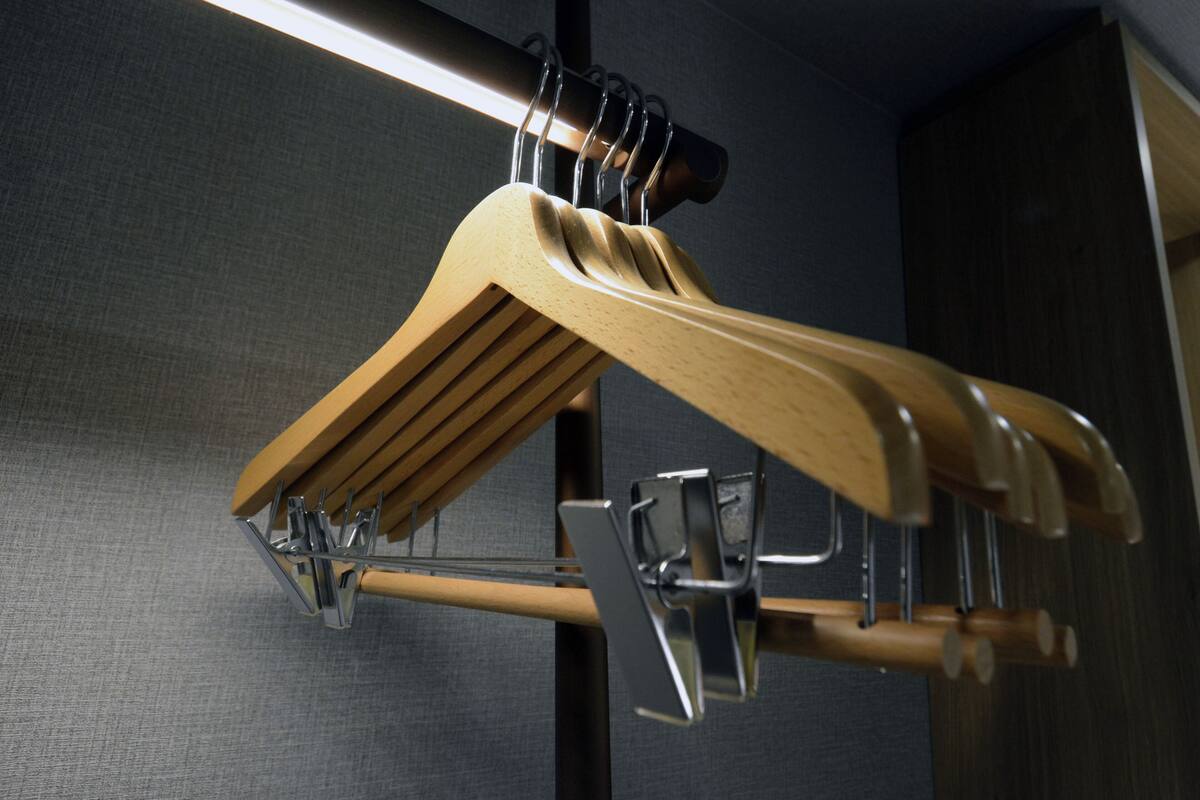 A wooden hanger with multiple pegs and a metal clip.