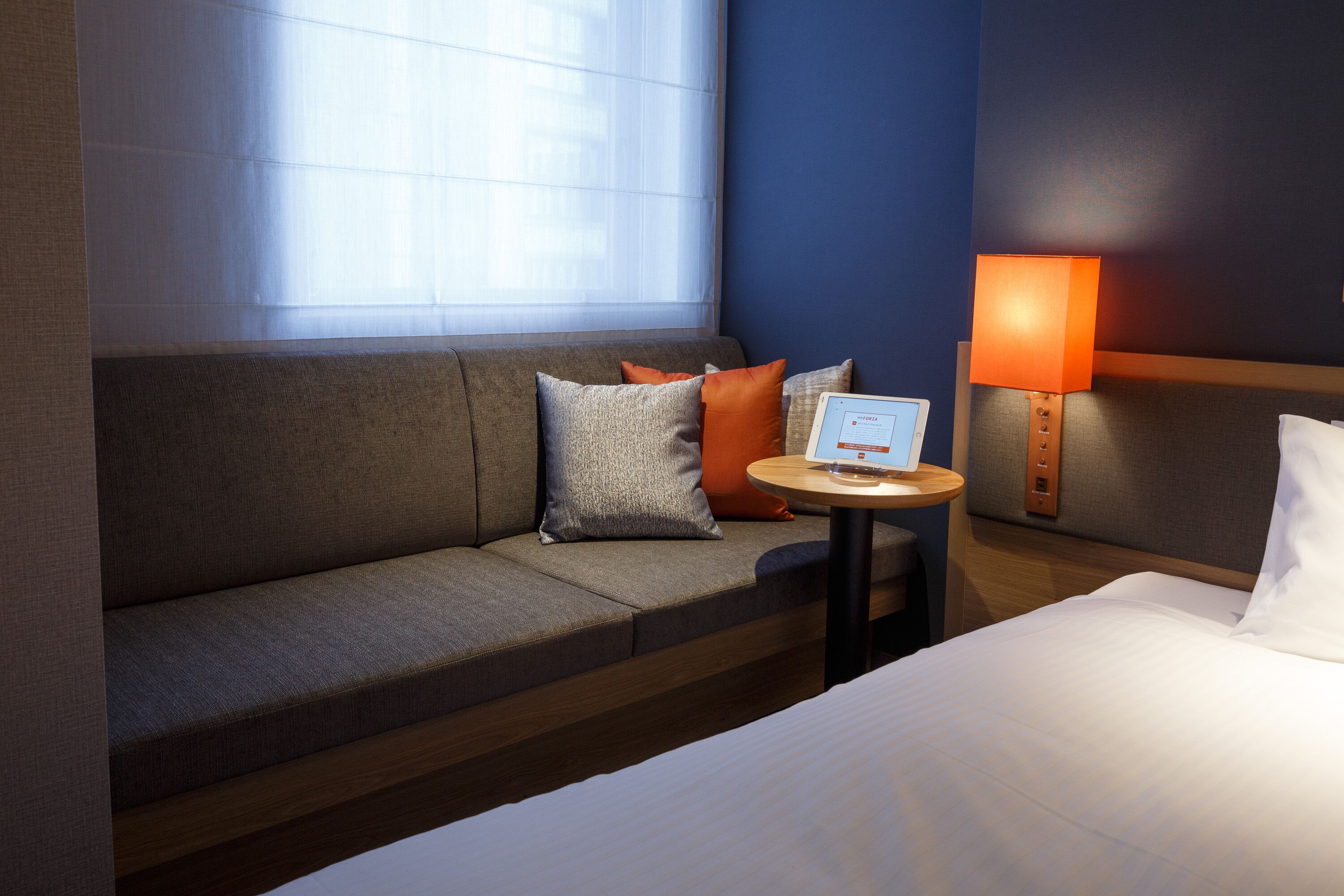 Una camera d'albergo con un divano, un piccolo tavolo con una lampada e un letto.