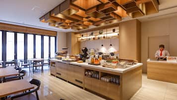 A modern breakfast area with wooden furniture, a central serving station, and large windows providing natural light.