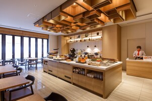 Un espace moderne dédié au petit-déjeuner, avec des meubles en bois, un buffet central et de grandes fenêtres qui laissent entrer la lumière naturelle.