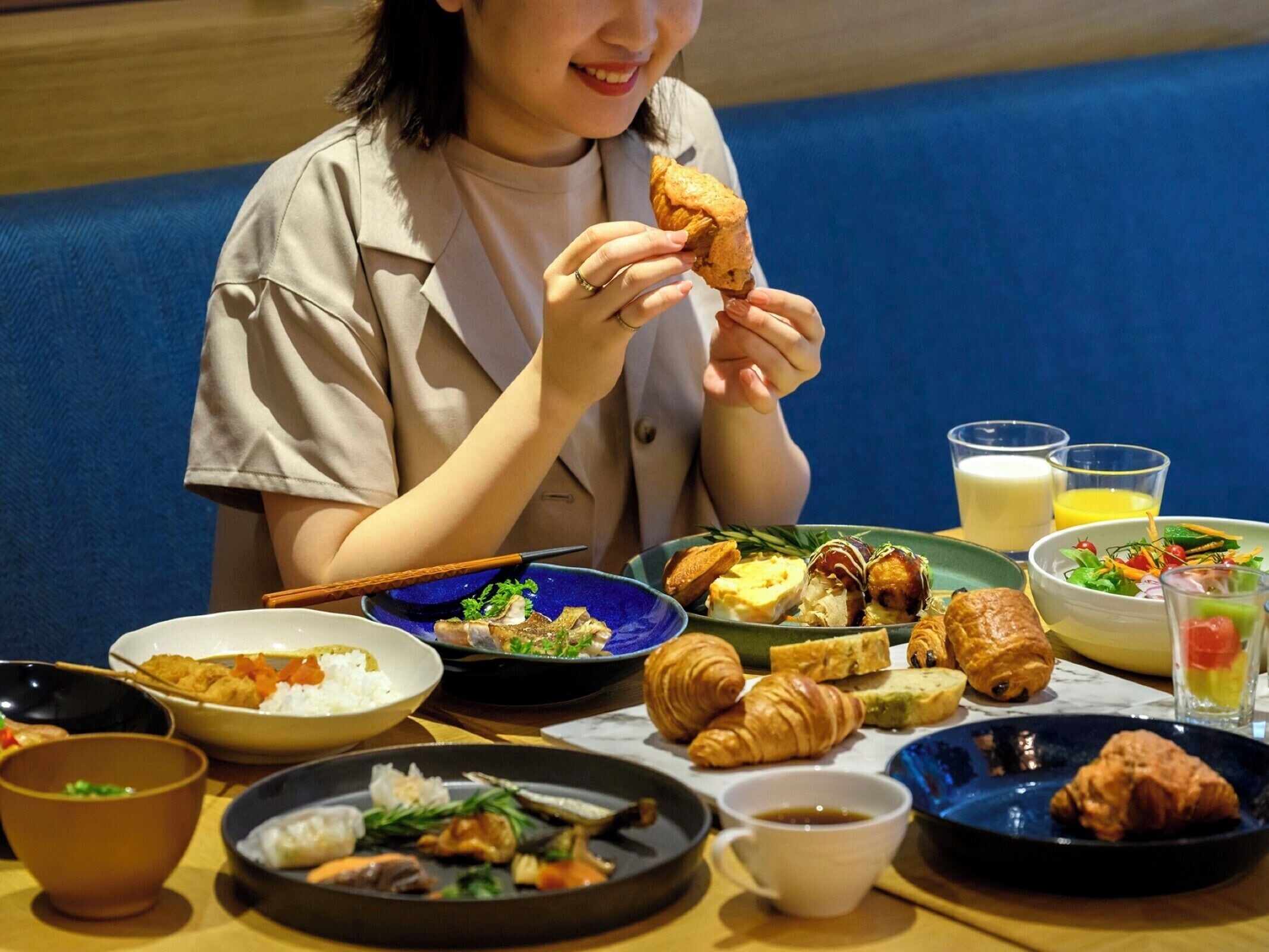 Una persona sentada a una mesa con varios platos, entre ellos arroz, sopa y pasteles.