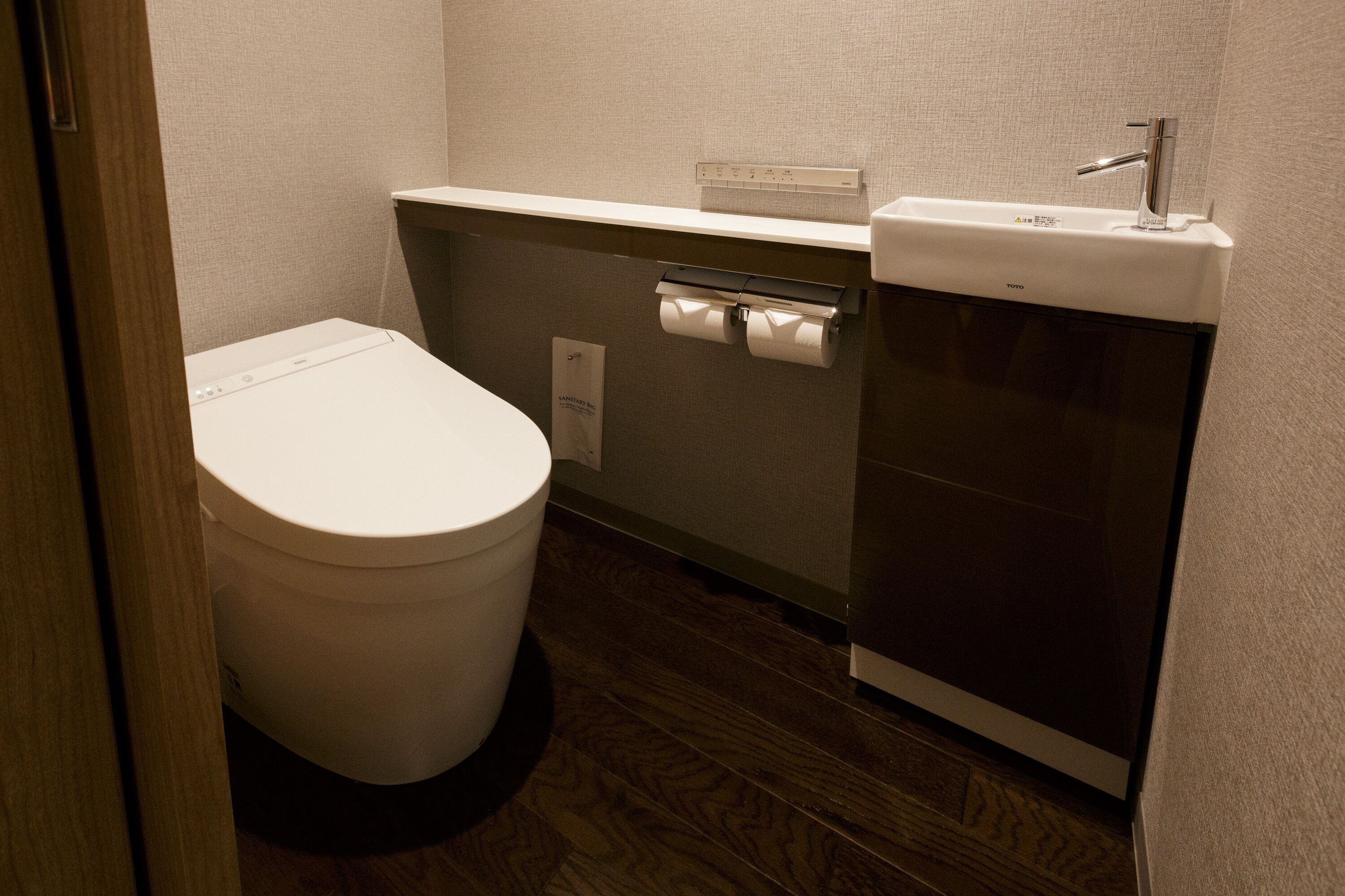 Un baño pequeño con inodoro, lavamanos y dispensador de toallas de papel.