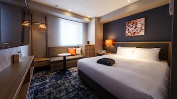 Ein Hotelzimmer mit einem großen Bett, einem Schreibtisch, einem kleinen Tisch, einer Couch, einer Lampe und einem Gemälde an der Wand.