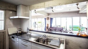 Una cocina con estufa, lavamanos y armarios. Hay un ventanal con vistas al exterior.