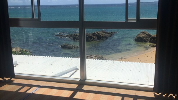 Una habitación con un ventanal grande que da a una playa y al océano.