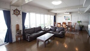Amplia sala de estar con sofás de cuero, una mesa de centro de madera y un comedor con sillas y una mesa.