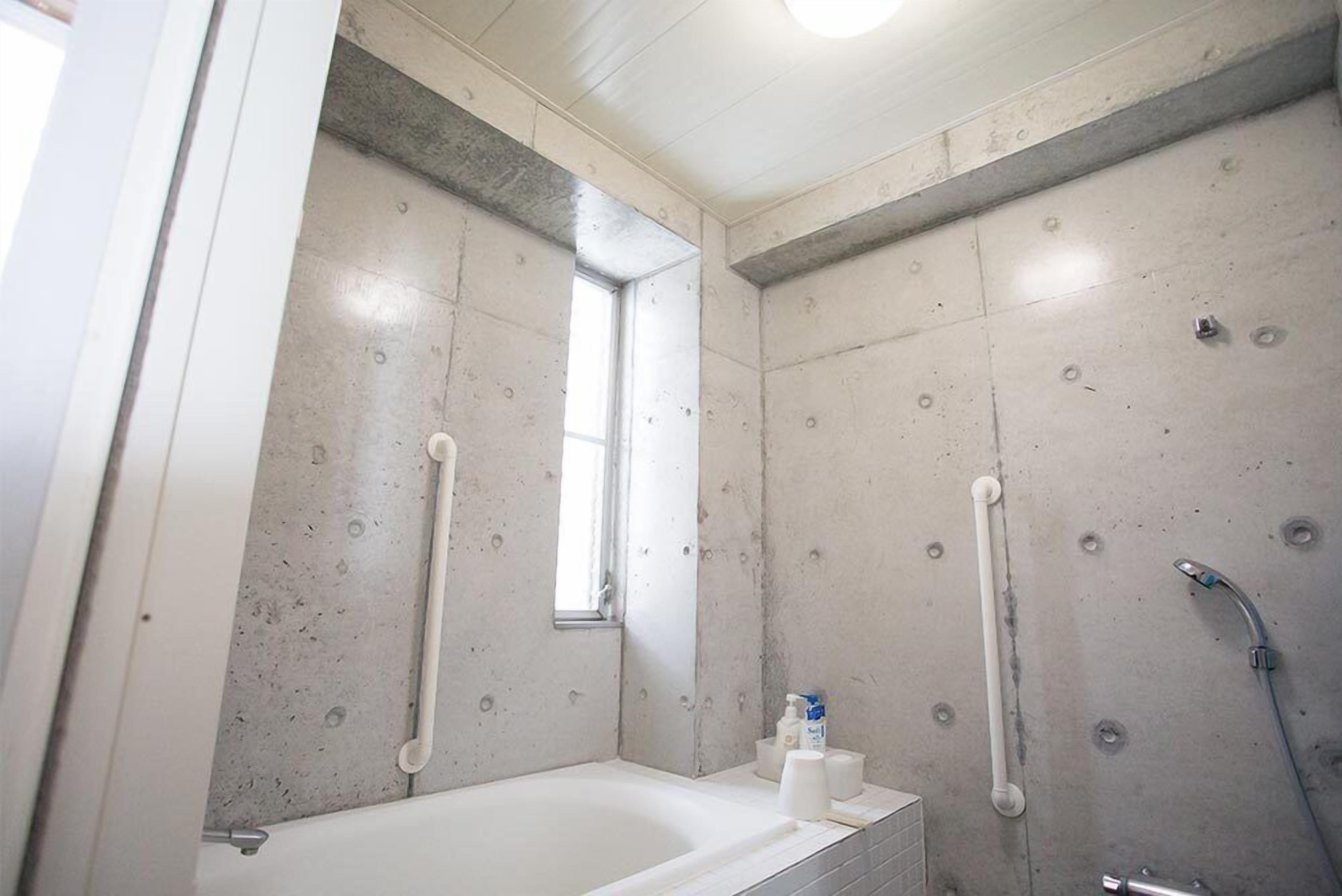 A bathroom with a bathtub, a shower, and a window.