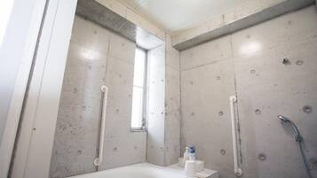 A bathroom with a bathtub, a shower, and a window.
