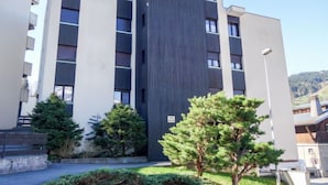 Un edificio moderno a più piani, con una facciata centrale scura e piani superiori bianchi.