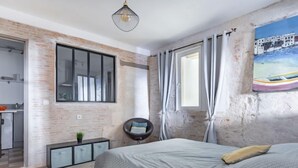 A bedroom with a large bed, a desk, and a chair. There is a window with curtains and a painting on the wall. - Bleu Bassin by Interhome (Arcachon)