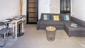 A modern living room with a grey sofa, a round coffee table, and a dining area with chairs and a table set for four. - Bleu Bassin by Interhome (Arcachon)