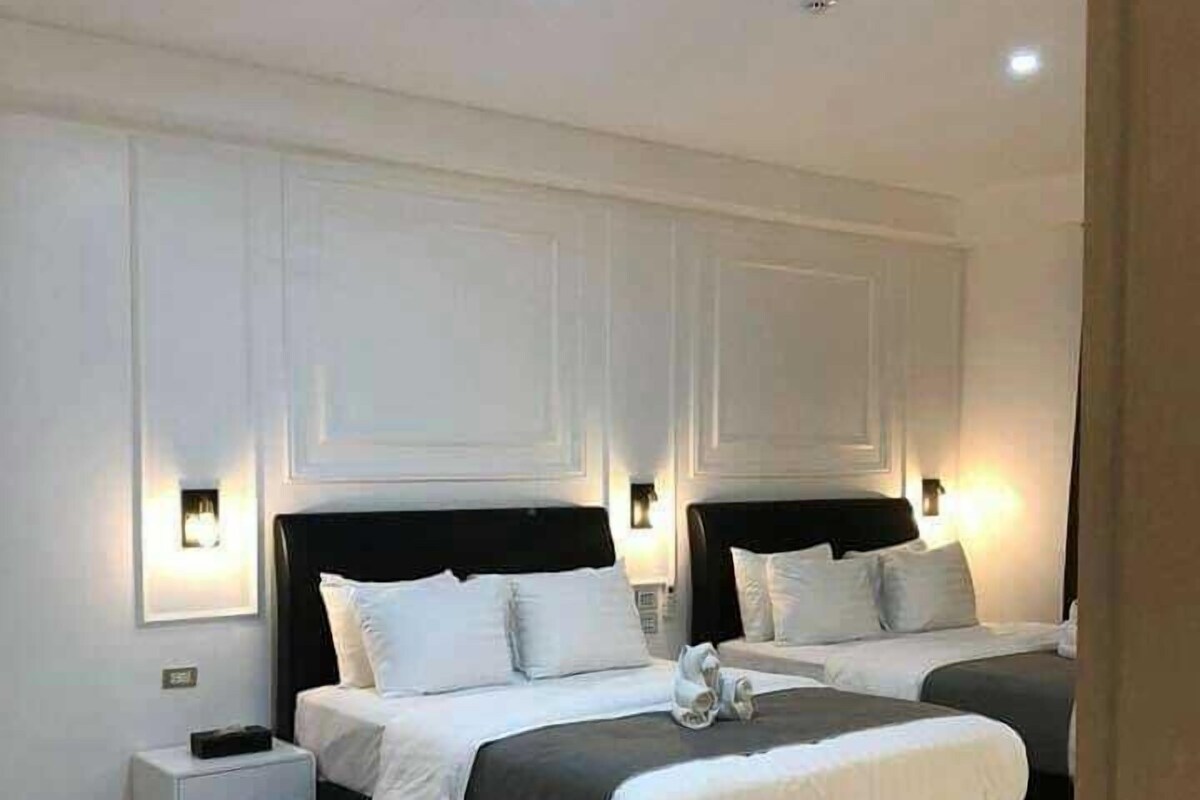 A modern bedroom with a large bed, bedside tables, and wall-mounted lighting.