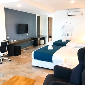 A hotel room with a bed, a desk, a chair, a TV, and an air conditioning unit.