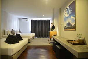 Una habitación de hotel moderna con cama, sofá, escritorio y un ventanal con cortinas.