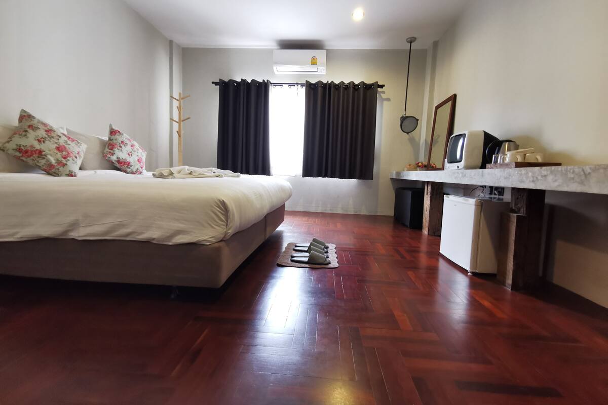 Quarto com cama, escrivaninha e janela com cortinas.