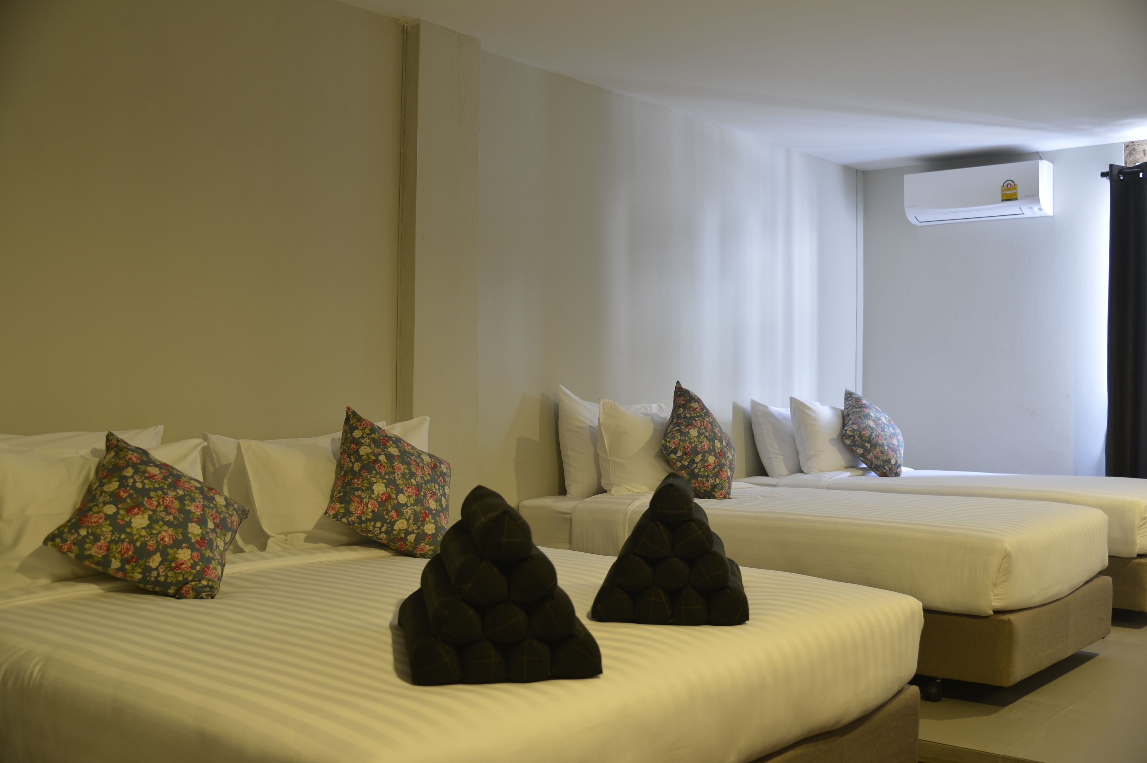 A hotel room with two beds, each with white bedding and decorative pillows.