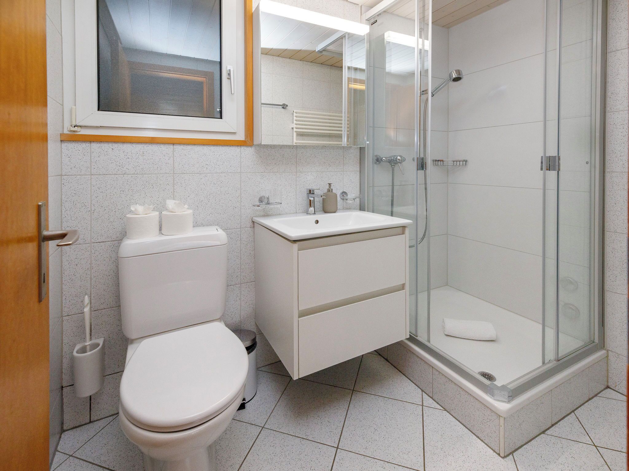 A modern bathroom with a toilet, sink, and glass-enclosed shower.