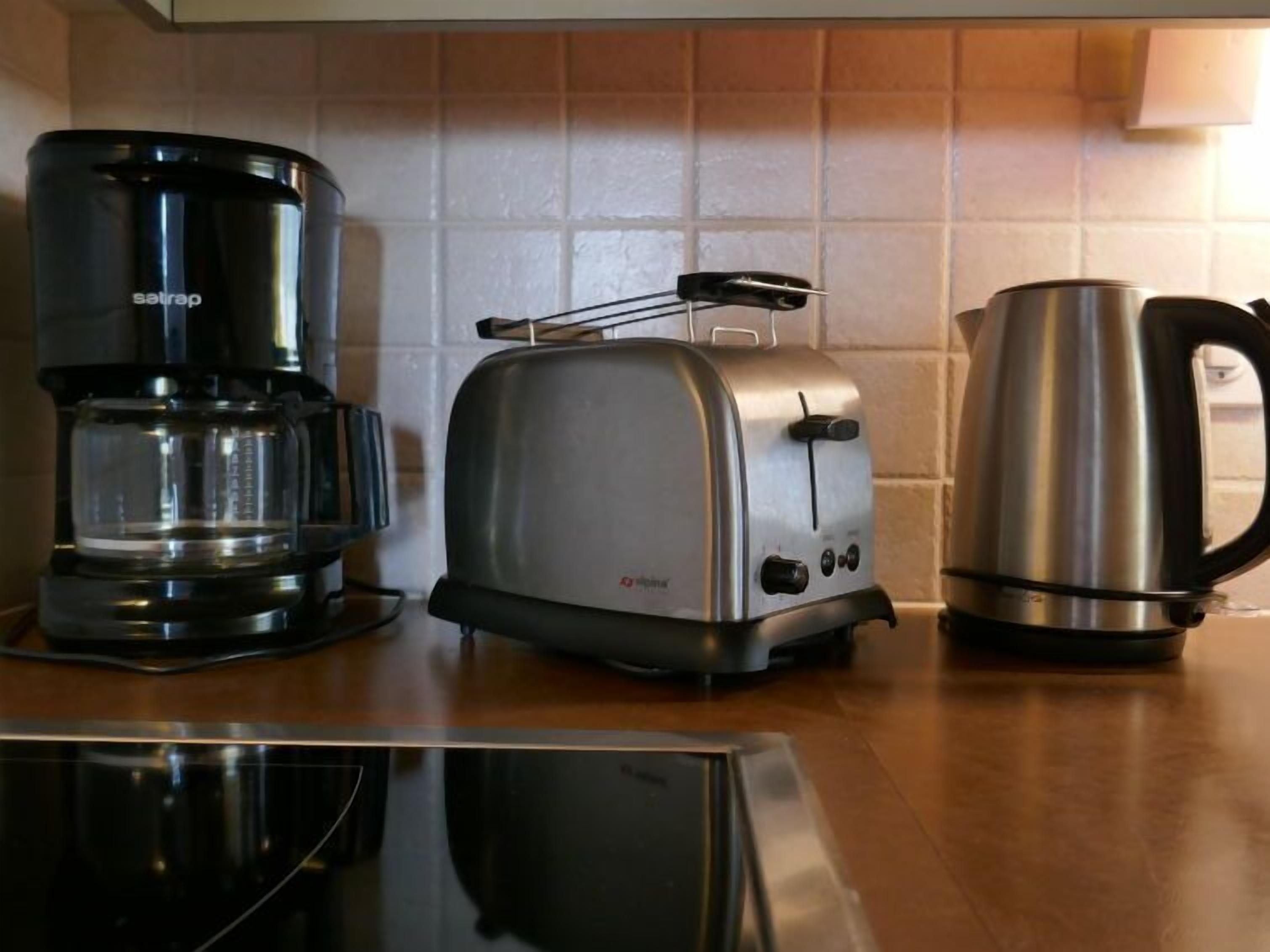Una cucina con macchina per il caffè, tostapane e bollitore sul piano di lavoro.