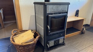 A wood-burning stove with a basket of firewood beside it. - Alphütte Bielerhüs by Interhome (Fiesch)
