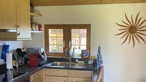 A kitchen with wooden cabinets, a stove, and a sink. - Alphütte Bielerhüs by Interhome (Fiesch)