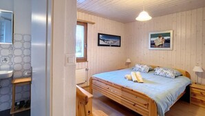 Une chambre à coucher avec un lit en bois, une table de chevet, une lampe et une fenêtre donnant sur un beau paysage.