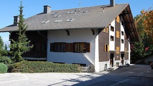 Un chalet à plusieurs étages, doté d’un toit en pente, de lucarnes et d’une cheminée.