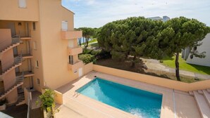 Un edifici residencial amb piscina, múltiples balcons i un gran arbre al pati.