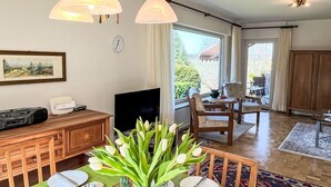 Un comedor con una mesa dispuesta para dos personas, un televisor y un reloj en la pared.