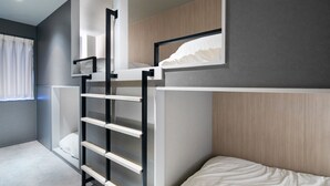 Een stapelbed met een ladder, een raam met gordijnen en een wandplank.