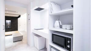 Een moderne keuken met witte kasten, een ingebouwde magnetron en een waterkoker op het aanrecht.