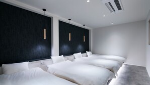 Een moderne hotelkamer met drie bedden, donkere wandpanelen en hanglampen.