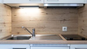 Eine moderne Küche mit Spüle aus Edelstahl, weißen Schränken und einer Holzrückwand.