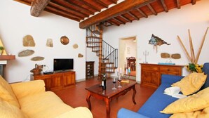 Una sala de estar amplia con una escalera de madera, un televisor y un comedor.