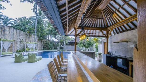 A poolside area with a wooden bar, seating, and a covered patio. - Villa 3# 1 BR Balinese Villa with public pool (Ubud)
