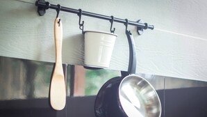 A kitchen with a black pot, a wooden spoon, and a white pot hanging on a rack. - Villa 3# 1 BR Balinese Villa with public pool (Ubud)