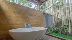 A modern bathroom with a freestanding bathtub, wooden panel wall, and a bamboo fence. - Villa 3# 1 BR Balinese Villa with public pool (Ubud)