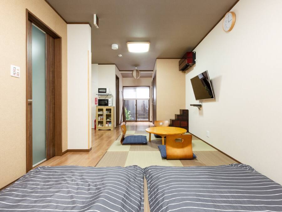 A hotel room with a bed, a small table, a TV, and a view of the outside.