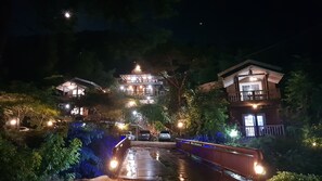 A traditional wooden building with multiple levels and a covered walkway, surrounded by lush greenery. - Goesan Namgang Pension (Goesan)