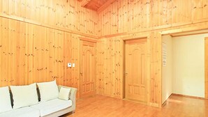 Quarto com paredes de painel de madeira, sofá branco e piso de madeira.