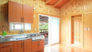 Interior de uma cabana de madeira com cozinha, incluindo armários, fogão e pia.