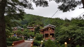Um conjunto de cabanas de madeira aninhadas numa encosta arborizada, com uma ponte que as acessa.